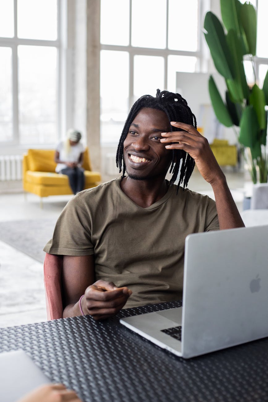 happy black man working on laptop in light coworking space